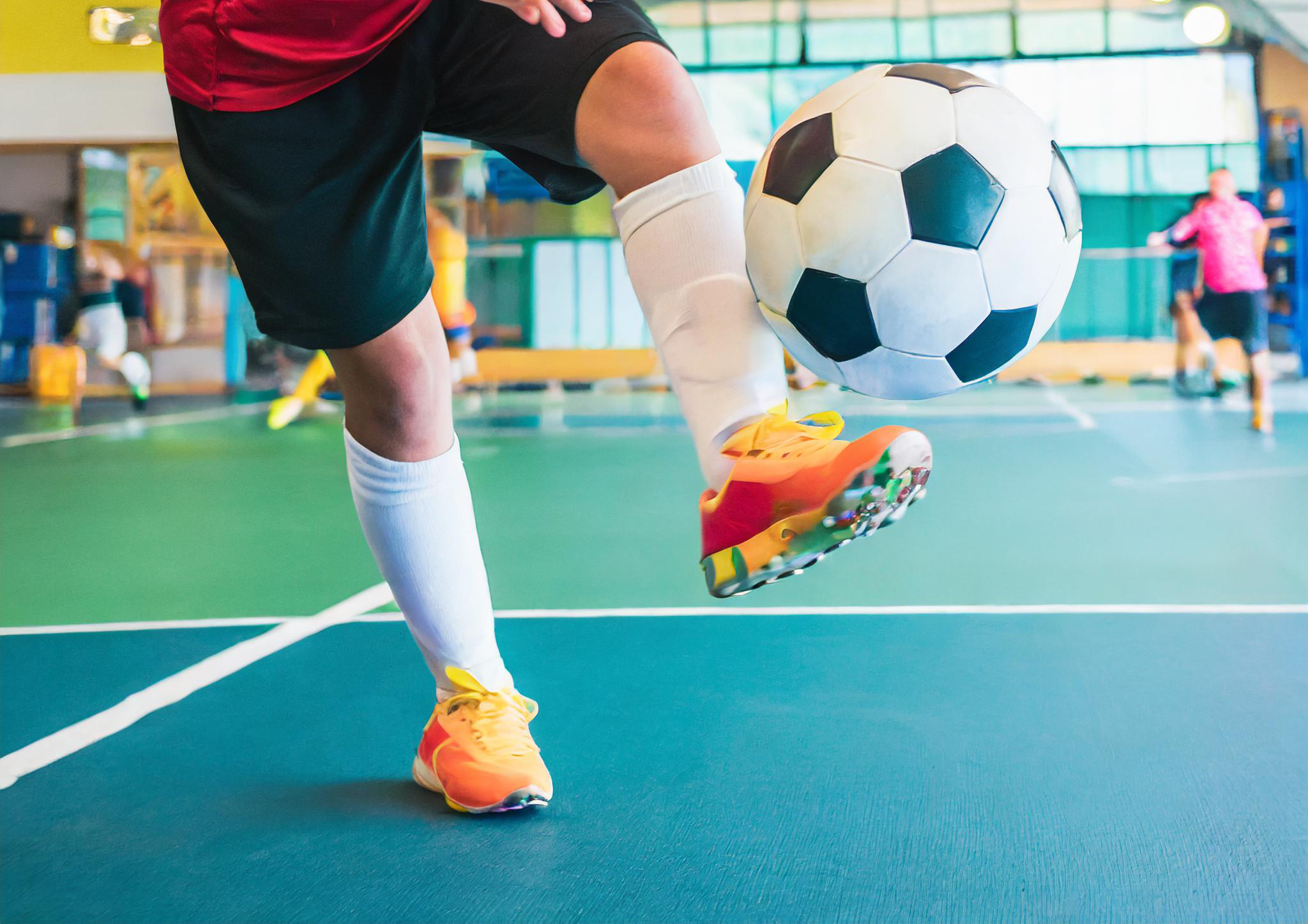 Girl kicking a soccerball in a gym